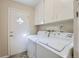 Laundry room features a side-by-side washer and dryer, upper cabinets, and a door to the exterior at 11754 W 28Th Ave, Lakewood, CO 80215