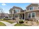 Exterior of home with stone accents, beige siding, small porch, and landscaped front yard at 9758 Laredo St # 18D, Commerce City, CO 80022