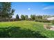 Expansive backyard featuring lush green grass, a wooden fence, and mature trees that provides lots of shade at 1043 Lilac Ct, Broomfield, CO 80020