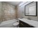 A tile-surrounded bathtub and vanity with a dark wood cabinet and modern mirror in this bathroom at 1043 Lilac Ct, Broomfield, CO 80020