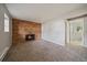 A living room with a brick fireplace, carpet, neutral walls, and an adjacent doorway to a laundry room at 1043 Lilac Ct, Broomfield, CO 80020
