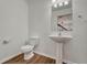 Clean powder room featuring pedestal sink, toilet, mirror, and hardwood floors at 17271 Waterhouse Cir # A, Parker, CO 80134