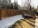 Fenced backyard with a wood deck, grass, and snow, offering a private outdoor space at 7456 E 10Th Ave, Denver, CO 80230