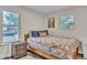 Bright bedroom with a wooden bed frame, colorful quilt, bedside table, and natural light from two windows at 3163 S Boston Ct, Denver, CO 80231