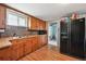 Charming kitchen featuring wood cabinetry, stone backsplash, double basin sink, and a black refrigerator at 5990 W 8Th Ave, Lakewood, CO 80214