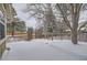 Snowy backyard with wooden fence and trees at 223 Durham Ct, Castle Pines, CO 80108