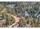 Dramatic aerial view of a mountain home surrounded by dense pine trees, showcasing privacy and seclusion at 10197 Crest View Dr, Morrison, CO 80465