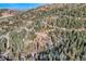 Breathtaking aerial view of a home set amongst a lush forest, with winding mountain roads nearby at 10197 Crest View Dr, Morrison, CO 80465