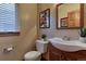 Well-lit bathroom featuring a window with blinds, a modern sink, and a toilet with decorative artwork at 10197 Crest View Dr, Morrison, CO 80465