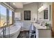 Modern bathroom featuring a standalone tub, spacious vanity, and a large window overlooking lush greenery at 10197 Crest View Dr, Morrison, CO 80465