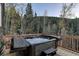 Back deck featuring a hot tub with forest views and outdoor seating at 10197 Crest View Dr, Morrison, CO 80465