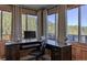 Home office featuring dark wood desk, ergonomic chair, and large windows providing natural light and beautiful wooded view at 10197 Crest View Dr, Morrison, CO 80465