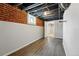 Basement room featuring durable wood-look floors and exposed brick at 3345 W Clyde Pl, Denver, CO 80211
