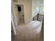 Bright upstairs hallway featuring tan carpet, stairs with black railing, and a laundry room at 10611 Casper St, Parker, CO 80134