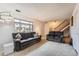 Bright living room featuring comfortable couches, a large window, and staircase access, ideal for modern living at 12407 E Louisiana Ave, Aurora, CO 80012