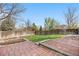 Fenced backyard featuring a brick patio, garden beds, and green space for outdoor enjoyment at 3055 E 133Rd Cir, Thornton, CO 80241