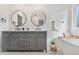 Modern bathroom features dual sinks, round mirrors, and a luxurious bathtub at 3055 E 133Rd Cir, Thornton, CO 80241