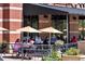 Outdoor restaurant seating area with tables, chairs, umbrellas and diners enjoying food and drink at 10111 Inverness Main St # 228, Englewood, CO 80112