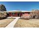A single-story red brick home with well-kept bushes, set against a clear blue sky at 2921 E Colorado Ave, Denver, CO 80210