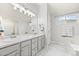 Well-lit Primary bathroom featuring double sinks, a vanity, and a tub with bright, natural light at 7888 Canvasback Cir, Littleton, CO 80125