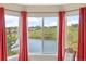 Bedroom window providing a scenic view of the lake and surrounding landscape, with red curtains framing the view at 7888 Canvasback Cir, Littleton, CO 80125