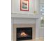 Cozy fireplace featuring tan tile surround and a decorative mantle with string lights and artwork above it at 7888 Canvasback Cir, Littleton, CO 80125