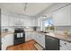 Kitchen with stainless steel appliances, white cabinets, granite counters, hardwood floors, and a window overlooking the backyard at 7888 Canvasback Cir, Littleton, CO 80125