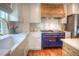 Gourmet kitchen with a stylish blue range, white cabinets, and a wooden range hood at 8140 S Storm King Peak, Littleton, CO 80127