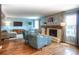 Bright living room features a stone fireplace with wooden beam, hardwood floors, and comfortable seating with blue accent chairs at 8140 S Storm King Peak, Littleton, CO 80127