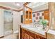 Elegant bathroom with granite counters, wood cabinets, a glass block shower and a neutral color palette at 6093 Willowbrook Dr, Morrison, CO 80465