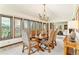 An elegant dining room features large windows with scenic views, a classic chandelier, and a spacious wooden table with seating for six at 6093 Willowbrook Dr, Morrison, CO 80465