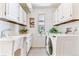 Well-lit laundry room with ample cabinet storage, utility sink, washer, and dryer provides convenience and organization at 6093 Willowbrook Dr, Morrison, CO 80465