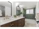 Bathroom with a double sink vanity with a dark cabinet, gold hardware, mirrors, and green subway tile in the shower at 4269 Carter Trl, Boulder, CO 80301