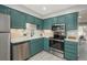 Updated kitchen featuring stainless steel appliances, white quartz countertops, and teal cabinetry at 11645 Lincoln St, Northglenn, CO 80233