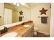 A bathroom with a granite countertop vanity and a large mirror. Decorated with star decor at 11506 Greenbriar Ln, Parker, CO 80138