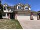 Charming two-story home featuring a three-car garage, brick accents, and well-manicured lawn at 11506 Greenbriar Ln, Parker, CO 80138