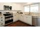 Bright kitchen featuring white cabinets, stainless steel appliances, granite countertops, and wood flooring at 11506 Greenbriar Ln, Parker, CO 80138