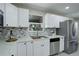 Updated kitchen with stainless steel appliances, white cabinets, and stylish backsplash at 2202 S Grape St, Denver, CO 80222