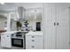 Modern kitchen featuring a center cooktop, white cabinetry, and stainless steel hood at 2202 S Grape St, Denver, CO 80222