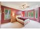 Bedroom featuring a large window, skylight, ceiling fan, and a red accent wall at 13314 Spruce Creek Cir, Larkspur, CO 80118