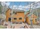 Backyard view of home with large deck area and mature trees and landscaping at 13314 Spruce Creek Cir, Larkspur, CO 80118