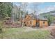 Rear of home with mature trees, open yard, and side deck at 13314 Spruce Creek Cir, Larkspur, CO 80118