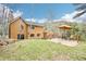 View of home from backyard with deck area, green grass, and mature trees at 13314 Spruce Creek Cir, Larkspur, CO 80118
