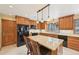 Well-lit kitchen features granite counters, wood cabinetry, black appliances, and an island with seating at 13314 Spruce Creek Cir, Larkspur, CO 80118