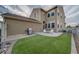 Backyard with a concrete patio, grill, white chairs, synthetic grass, and partial view of the house at 21682 E Stroll Ave, Parker, CO 80138
