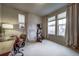 Bedroom with beige carpet, desk, workout machine, and large windows with curtains allowing natural light at 21682 E Stroll Ave, Parker, CO 80138