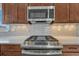 Close-up of a kitchen range with stainless steel appliances and a light gray tiled backsplash at 6957 Black Forest Dr, Elizabeth, CO 80107