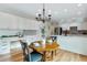 Open concept kitchen with white cabinets, patterned backsplash, island seating, and modern light fixture at 8645 Coors St, Arvada, CO 80005