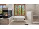 Bright bathroom featuring a soaking tub, a fireplace, and a large window with beautiful outdoor views at 858 Swandyke Dr, Castle Rock, CO 80108