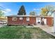 The home's backyard features a small patio, lush green grass, and mature trees in a serene setting at 6506 Lee St, Arvada, CO 80004